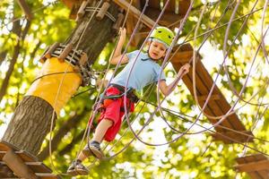 petits enfants heureux dans un parc à cordes sur fond de bois photo