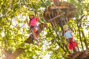 petits enfants heureux dans un parc à cordes sur fond de bois photo