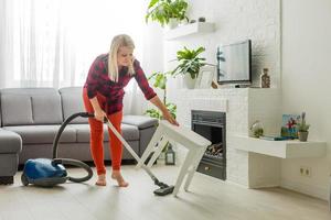 jeune femme utilisant un aspirateur à la maison. photo