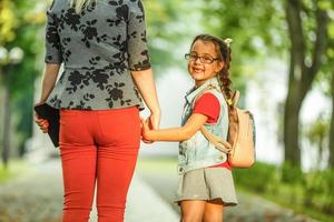 enfant qui retourne à l'école. début de la nouvelle année scolaire après les vacances d'été. petite fille avec sac à dos et livres le premier jour d'école. début de classe. éducation pour les enfants de la maternelle et du préscolaire. photo