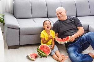 grand-père et petite-fille mangent de la pastèque à la maison photo