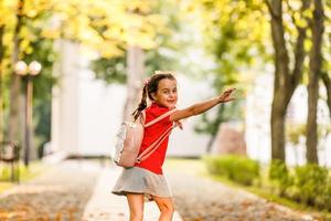 la petite écolière court avec un sac à dos et rit. le concept d'école, d'étude, d'éducation, d'amitié, d'enfance. photo