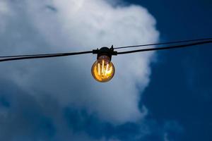 gros plan d'un filament de style edison sur une ampoule contre un ciel nuageux. crise de l'énergie. photo