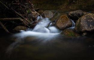 un petit ruisseau forestier avec des falaises de grès et des pierres photo