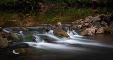 un petit ruisseau forestier avec des falaises de grès et des pierres photo