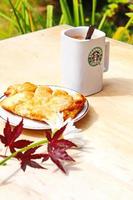 washington, états-unis - 01 août 2022 tasse à café avec logo starbucks sur le devant, boulangerie blanche sur assiette. placez-le sur une table en bois dans le jardin où le soleil du matin brille. photo