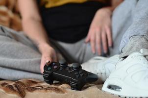 contrôleur de jeu noir moderne entre les mains d'une jeune fille assise photo