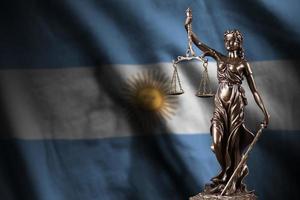 drapeau argentin avec statue de dame justice et balance judiciaire dans une pièce sombre. concept de jugement et de punition photo