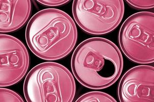 de nombreuses canettes de boissons gazeuses ou de boissons énergisantes. beaucoup de canettes recyclées en aluminium. image tonique en viva magenta, couleur de l'année 2023 photo