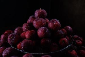 assiette complète de pommes rouges fraîches. beaucoup de pommes mûres dans le bol et autour. photo