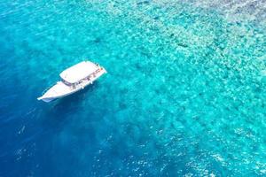 vue aérienne imprenable, côte de l'île tropicale avec corail et plage aux maldives. incroyable récif corallien et belle vue aérienne sur la mer bleue et les eaux peu profondes. concept de vacances de vacances d'été, voyage exotique photo