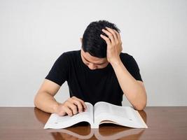 un homme asiatique sérieux au sujet de la lecture d'un manuel pour le test se sent essayé photo