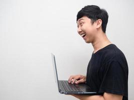 homme asiatique souriant et utilisant la vue latérale d'un ordinateur portable photo