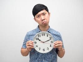 homme asiatique confus et doute tenant une horloge analogique suis isolé photo