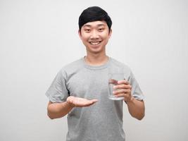 jeune homme positif tenant un médicament avec un verre d'eau doux sourire isolé photo