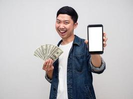 chemise jeans homme asiatique sourire heureux tenir de l'argent et montrer le smartphone à la main photo