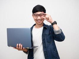 portrait homme portant des lunettes sourire heureux tenant un ordinateur portable regardant la caméra, jeune homme d'affaires jeans chemise isolée photo