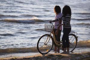 vélo de silhouette et couple amoureux pendant les vacances à l'heure du lever du soleil au bord d'un lac photo
