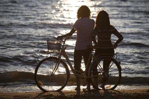 vélo de silhouette et couple amoureux pendant les vacances à l'heure du lever du soleil au bord d'un lac photo