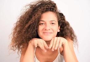 femme aux cheveux bouclés et belle peau de visage saine regarde la caméra et pose. notion de beauté photo