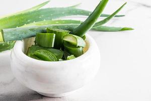 tranches d'aloe vera frais et juteux dans un mortier blanc en marbre pour la préparation d'un remède naturel cosmétique à la maison. premier plan. photo