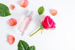 composition florale avec un élégant flacon de parfums féminins et pétales de rose, bouton floral. mise à plat. vue de dessus. fond blanc. présentation des arômes. photo