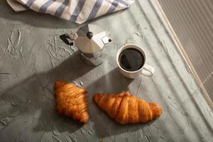 petit-déjeuner avec croissant et cafetière et moka. concept de repas du matin et de petit-déjeuner. vue de dessus. photo