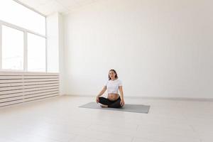 belle femme enceinte en bonne santé médite avant le cours de yoga et se détend assise sur un tapis au sol. concept de préparation physique et mentale du corps à l'accouchement. fond photo