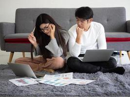 homme d'affaires couple, femme et homme assis ensemble à la maison à l'aide d'un ordinateur portable pour une réunion en ligne avec le travail d'équipe de démarrage. jeune femme d'affaires asiatique travaillant, planifiant ou discutant avec un collègue. photo