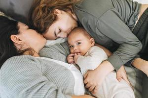 vraie famille de jeune maman et de deux enfants d'âges différents adolescente et bébé garçon s'amusant sur le lit photo