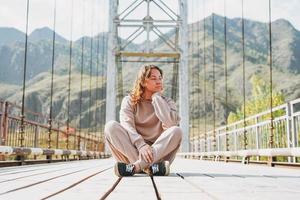 jeune femme voyageuse en tenue décontractée assise sur le pont horochowski sur la rivière katun photo