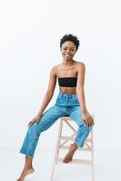portrait de la belle jeune femme afro-américaine en haut noir et jeans bleus isolés sur fond blanc photo