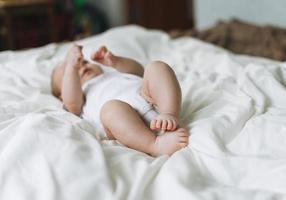 jolie petite fille de 2 à 4 mois sur le lit avec des draps blancs, des tons naturels, une mise au point sélective photo