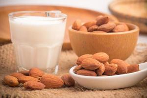 lait d'amande en verre avec des amandes sur une table en bois photo