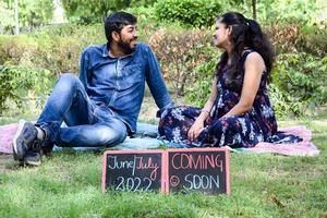 couple indien posant pour une séance photo de maternité. le couple pose dans une pelouse avec de l'herbe verte et la femme étale sa bosse de bébé dans le jardin de lodhi à new delhi, inde