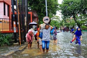 semarang, décembre 2022. plusieurs personnes transportent des sacs remplis de nourriture et de vêtements pour se préparer à l'évacuation après l'inondation de leur maison photo