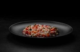 délicieux risotto frais aux légumes, épices et herbes sur une plaque noire photo