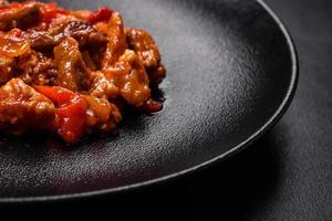 délicieuse viande juteuse avec piments et sauce sur une plaque en céramique noire photo