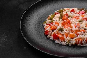 délicieux risotto frais aux légumes, épices et herbes sur une plaque noire photo