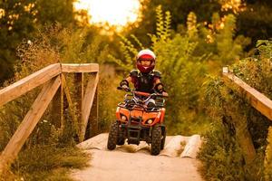 heureuse petite fille jouant sur la route pendant la journée. il conduit en quad dans le parc. enfant s'amusant sur la nature. notion de bonheur. photo