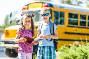 rire souriant garçon caucasien étudiant enfant avec drôle d'expression de visage marchant près du bus jaune le 1er septembre. concept d'éducation et de retour à l'école. enfant élève prêt à apprendre et à étudier. photo