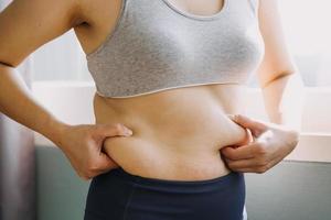 belle grosse femme avec ruban à mesurer, elle utilise sa main pour presser l'excès de graisse isolé sur fond blanc. elle veut perdre du poids, le concept de chirurgie et décomposer les graisses sous le photo