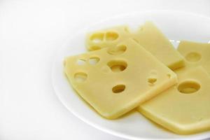 morceaux de fromage avec des trous sur une assiette blanche. tranches de fromage avec de gros trous. délicieux fromage sur une assiette. photo