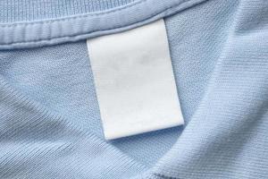 étiquette blanche de vêtements de soin de blanchisserie vierge sur fond de tissu de chemise bleue photo