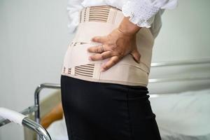 patiente asiatique portant une ceinture de soutien des maux de dos pour lombaire orthopédique avec marchette. photo