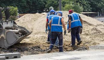 travailleurs de la route en uniformes bleus et casques sur le trottoir photo