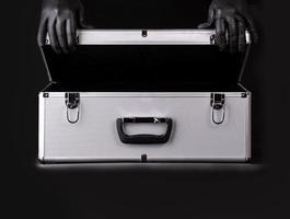 grande valise en aluminium et mains gants de sécurité noirs photo