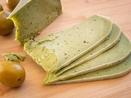 savoureux fromage pesto vert et olives sur une planche à découper en bois gros plan photo