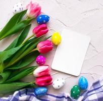 ester heureux. oeufs de couleur avec des tulipes sur la vue de dessus de fond gris photo