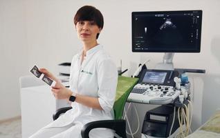 portrait d'un médecin obstétricien assis dans la salle de clinique avec appareil à ultrasons photo